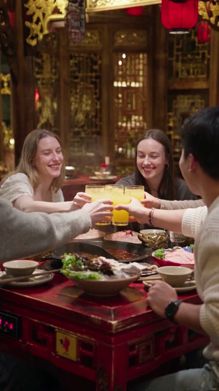 A group of diners sharing a toast around the hot-pot table